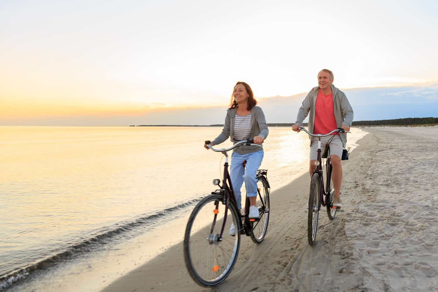 senior couple cycling on beach